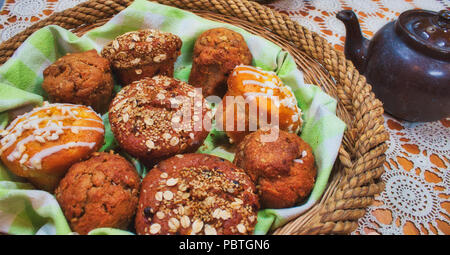 Korb mit frisch gebackenen Muffins auf einem Tisch mit einer Teekanne Stockfoto