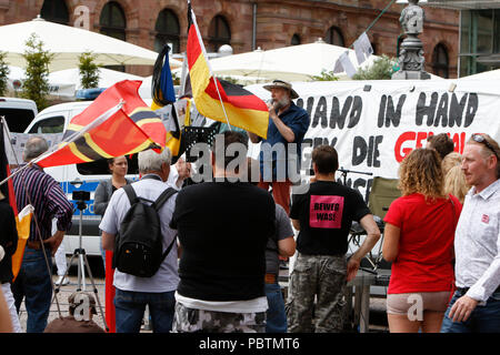 Wiesbaden, Deutschland. 29. Juli, 2018. Rechtsradikale Demonstranten hören den Reden. Rechtsextreme Demonstranten der Hand in Hand-Gegen die Gewalt in unseren Strasen (Hand in Hand - gegen Gewalt auf unseren Straßen) Bewegung statt einer regierungsfeindlichen Kundgebung in Wiesbaden. Dieser Protest war unter dem Vorwand, eine Mahnwache für den Jugendlichen Susanna F, der angeblich von einem Flüchtling in Wiesbaden getötet wurde. Die Kundgebung wurde von mehreren Anti-government Referenten, die forderte, dass die Regierung zum Rücktritt gerichtet. Quelle: Michael Debets/Pacific Press/Alamy leben Nachrichten Stockfoto