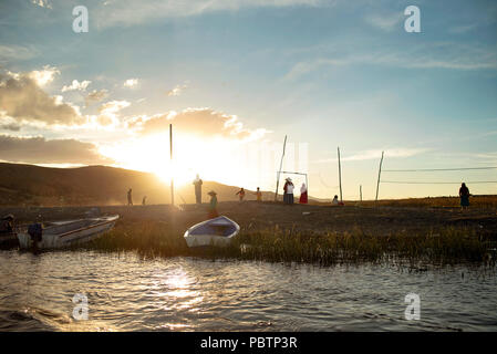 Jungen Fußball spielen auf dem Feld aus Totora Schilfgras (dass die Inseln konstruieren). Sonnenuntergang über Las Islas Flotantes, Titicacasee, Peru. Jun 2018 Stockfoto