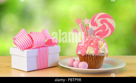 Pink Thema bunte Neuheit Cupcake mit Süßigkeiten und großen herzförmigen Lutscher gegen Garten Hintergrund für Kinder oder Teenager Geburtstag eingerichtet, Stockfoto