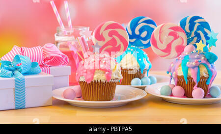 Drei rosa und blau Thema bunte Neuheit cupcakes dekoriert mit Süßigkeiten und grosse herzförmige Lollis für Kinder, jugendlich Geburtstag oder Urlaub c Stockfoto