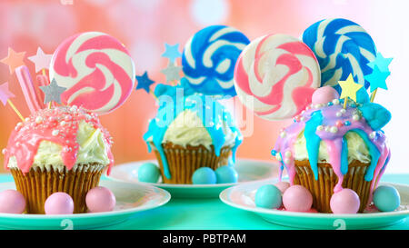 Drei rosa und blau Thema bunte Neuheit cupcakes dekoriert mit Süßigkeiten und grosse herzförmige Lollis für Kinder, jugendlich Geburtstag oder Urlaub c Stockfoto