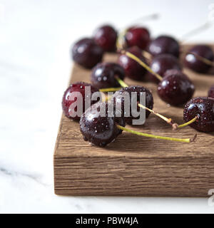 Wassertropfen auf der natürlichen organischen Kirsche auf Holzbrett. Konzept od klare gesunde Essen. Stockfoto