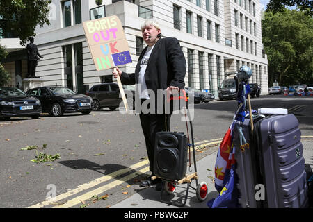 Carlton Gardens, Westminster, London, UK, 30. Juli 2018. Faux Bojo, komplett mit beweglichen Taschen, (Drew Galdron, Boris Imitator) dreht sich oben am Umzugstag Boris aus dem Wohnheim zu verleiten. Ausbau Vans gesehen laden Möbel und Gegenstände an den ehemaligen Außenminister Boris Johnson London's Residence in Carlton Gardens, Westminster. Johnson hatte das Anwesen zu verlassen da unten von seinem ministerposten. Credit: Imageplotter Nachrichten und Sport/Alamy leben Nachrichten Stockfoto