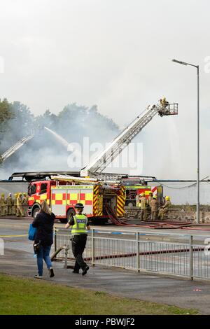 Glasgow, UK. 30. Juli, 2018. Glasgow, Schottland, Großbritannien. Ein großes Feuer Kräfte die Schließung von Crookston Rd in Glasgow als Feuerlöschfahrzeuge säumen die Straße und die Brandbekämpfung Umluftunabhängiges Atemschutzgerät verwenden und hohe Reichweite Plattformen den Brand zu bekämpfen. Quelle: Douglas Carr/Alamy leben Nachrichten Stockfoto