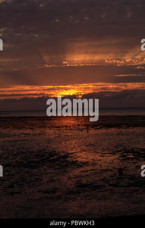 Hampton, Herne Bay, Großbritannien. 30. Juli 2018. Nach drei Tagen des kalten, stürmischen Wetter und Regen mit Wind, die Sonne bricht durch und die Temperaturen steigen, die glühende Sonnenuntergänge über der Mündung der Themse als Menschen nutzen das Wetter ändern, um am Strand zu Fuß gehen. Richard Donovan/Alamy leben Nachrichten Stockfoto