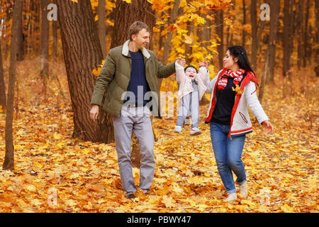 Junge Eltern gehen und spielen mit kleinen Tochter im Herbst Park. Papa und Mama mit Baby. Happy Family Konzept Stockfoto