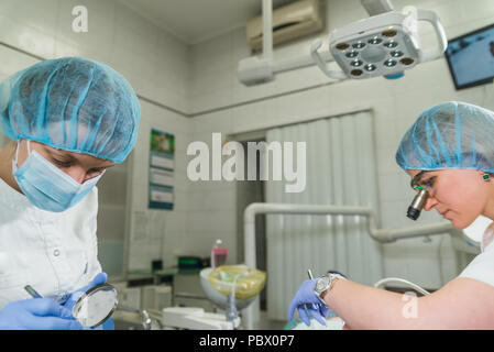 Frau beim Zahnarzt Klinik erhält der zahnmedizinischen Behandlung ein Loch in einen Zahn zu füllen. Zahnersatz und Verbundmaterial Polymerisation mit UV-Licht und Laser. Stockfoto