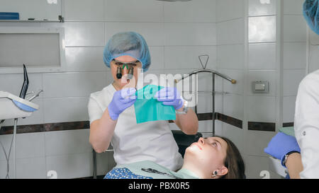 Frau beim Zahnarzt Klinik erhält der zahnmedizinischen Behandlung ein Loch in einen Zahn zu füllen. Zahnersatz und Verbundmaterial Polymerisation mit UV-Licht und Laser. Stockfoto