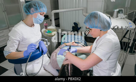 Frau beim Zahnarzt Klinik erhält der zahnmedizinischen Behandlung ein Loch in einen Zahn zu füllen. Zahnersatz und Verbundmaterial Polymerisation mit UV-Licht und Laser. Stockfoto