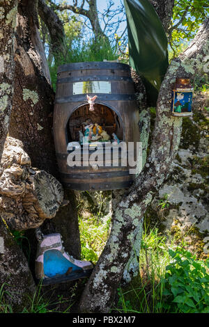 Kruzifixe in ungewöhnlichen Behälter ein Fass und kleine in einem Baum an der Wallfahrtskirche Santa Maria de Finestres, in der Nähe der Santa Pau, Catalunya, spai Nullförderung Stockfoto