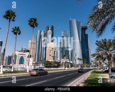 DOHA, Katar - Feb 2018: Straße mit Palmen Kopf zu modernen Blau hohe Wolkenkratzer in der Stadt Doha, Katar Stockfoto