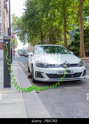 London, England, UK; 27. Juli 2018; Weiß Volkswagen Golf GTE Plug-In Hybrid Electric Car Laden in einem Londoner Straße. Stockfoto