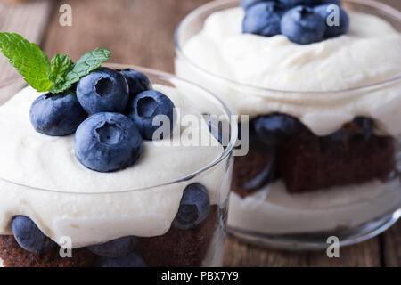 Heidelbeere Schokolade Kuchen Kleinigkeit in Glas auf rustikalen Holztisch, köstliche Sommer Dessert Stockfoto