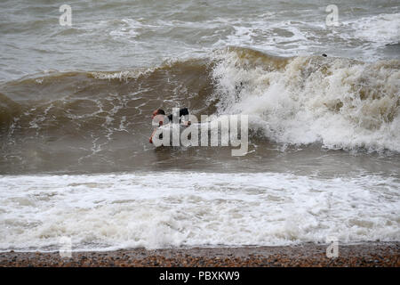 Ein Surfer in Brighton Beach, nach starkem Regen in den vergangenen Tagen bedeutet in diesem Monat ist auf der Schiene bis zu Ende Wetter als im Juli 1976. Stockfoto