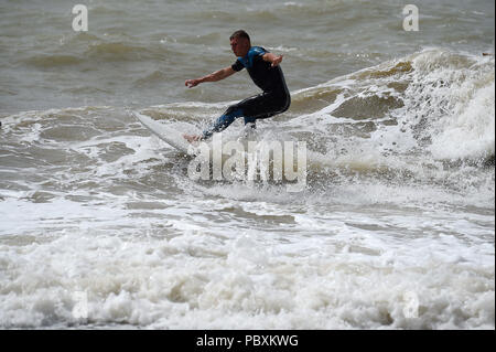 Ein Surfer in Brighton Beach, nach starkem Regen in den vergangenen Tagen bedeutet in diesem Monat ist auf der Schiene bis zu Ende Wetter als im Juli 1976. Stockfoto