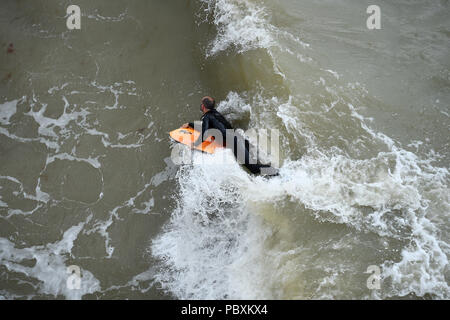 Ein Surfer in Brighton Beach, nach starkem Regen in den vergangenen Tagen bedeutet in diesem Monat ist auf der Schiene bis zu Ende Wetter als im Juli 1976. Stockfoto