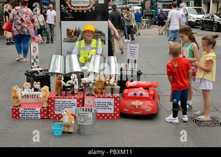 Kinder werden vom Techno Tin bin man Busker in der Argyle Street, Glasgow Stadtzentrum, Schottland, Großbritannien, unterhalten Stockfoto