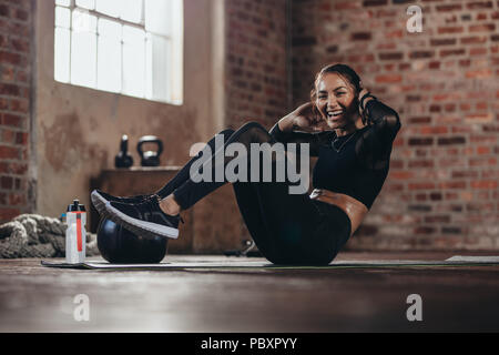 Passen junge Frau tun Knirschen workout Ihren abs zu verbessern. Lächelnd weibliche in der Turnhalle tun, Sit-up Übung im Fitnessstudio. Stockfoto