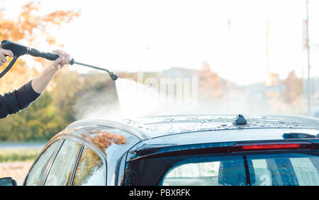 Arbeitnehmer Reinigung Auto mit hohem Druck Wasser Düse Stockfoto