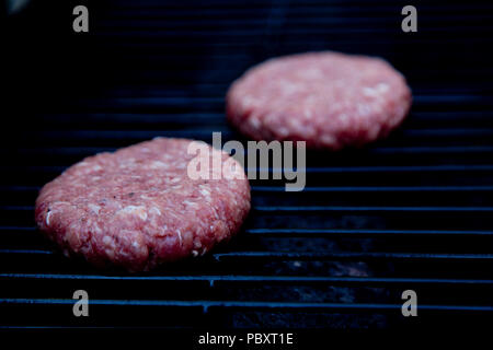 Raw beefburgers auf dem Grill zubereitet werden. Stockfoto