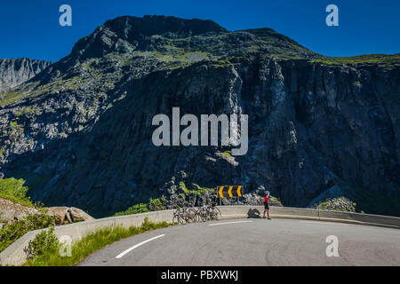 Weibliche Radfahrer mit zwei Fahrräder stehen auf einem der Serpentinen auf den trollstigen Pass, in der Nähe von Molde, Norwegen Stockfoto