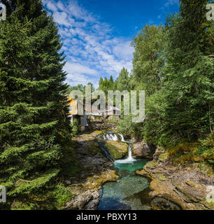 Gelbe Holzhäuser, neben einem kleinen Wasserfall, in der Nähe von Voss, Norwegen Stockfoto