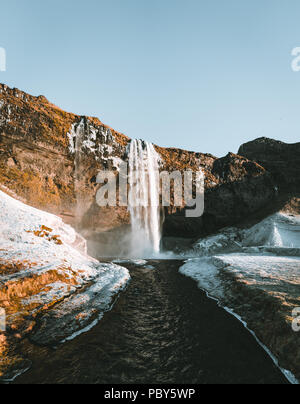 Wunderbare Landschaft von Wasserfall Seljalandsfoss in Island an einem klaren Tag mit blauem Himmel und Schnee. Stockfoto