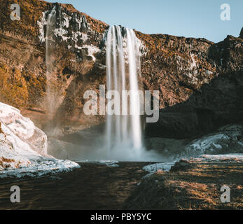 Wunderbare Landschaft von Wasserfall Seljalandsfoss in Island an einem klaren Tag mit blauem Himmel und Schnee. Stockfoto