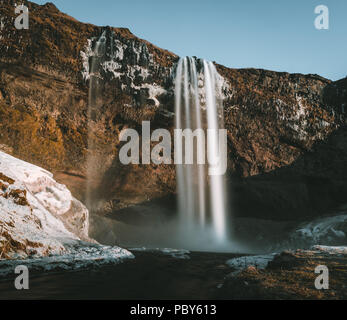 Wunderbare Landschaft von Wasserfall Seljalandsfoss in Island an einem klaren Tag mit blauem Himmel und Schnee. Stockfoto