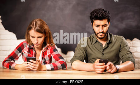 Junge paar schöne Sitzung mit Smartphones und schriftliche Meldungen in den Büros Stockfoto
