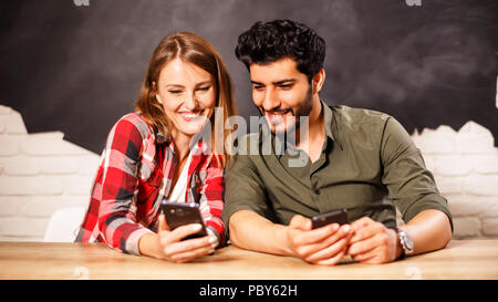 Glückliches junges Paar schöne saßen und verschiedene Fotos in das Smartphone im Büro Stockfoto