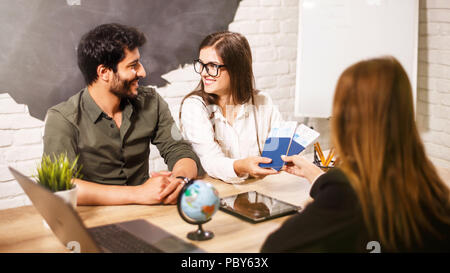 Junge paar schöne sitzend mit Manager im Reisebüro Büro prepairing für einen Sommerurlaub Stockfoto