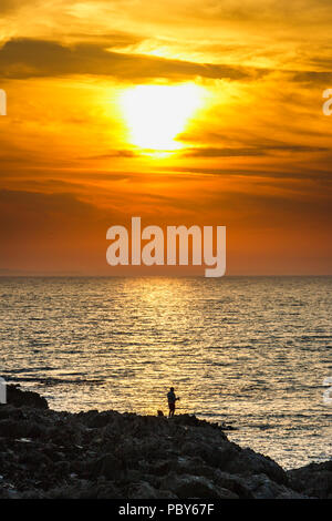 Ein Meer Winkel auf Felsen Silhouette gegen einen dramatischen Sonnenuntergang am Westward Ho!, Devon, Großbritannien Stockfoto