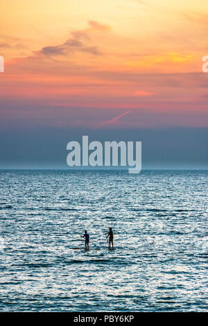 Zwei paddleboarders Silhouette gegen den Sonnenuntergang am Westward Ho!, Devon, Großbritannien Stockfoto