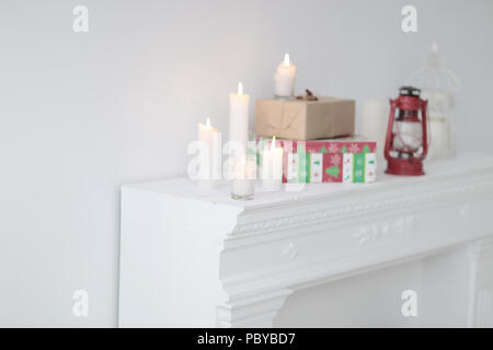 Unscharfes Bild. Kerzen und Geschenkboxen auf dem Kamin im Wohnzimmer. Foto mit Kopie Raum Stockfoto