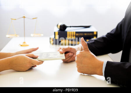 Rechtsanwalt angeboten wird Geld empfangen als Schmiergeld Client am Schreibtisch im Gerichtssaal Stockfoto