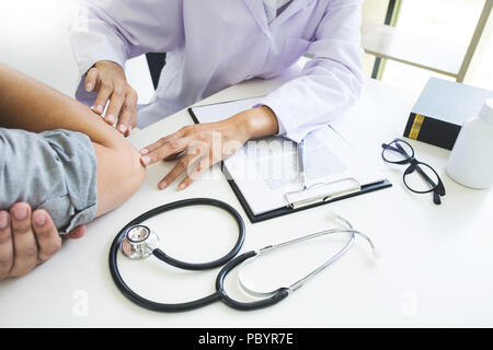 Attraktive männlicher Arzt Untersuchung über Berichte mit Massage Patient leidet unter Rückenschmerzen in Klinik Stockfoto