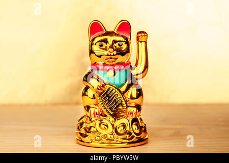 Maneki Neko, Japanisch lucky Beckoning Cat-Figur, auf einem goldenen Hintergrund mit Kopie Raum Stockfoto