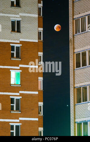 Mondfinsternis im Vollmond. Super blaues Blut Mond im Juli 27, 2018, Belarus. Stadtbild: Fassade eines mehrstöckigen Gebäude vor dem Hintergrund der Stockfoto