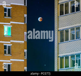 Mondfinsternis im Vollmond. Super blaues Blut Mond im Juli 27, 2018, Belarus. Stadtbild: Fassade eines mehrstöckigen Gebäude vor dem Hintergrund der Stockfoto