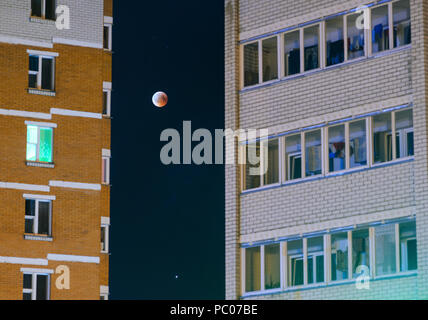 Mondfinsternis im Vollmond. Super blaues Blut Mond im Juli 27, 2018, Belarus. Stadtbild: Fassade eines mehrstöckigen Gebäude vor dem Hintergrund der Stockfoto