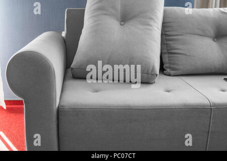 Komfortable grau Couch in ein Wohnzimmer mit blauen Wand und roten Boden. Stockfoto