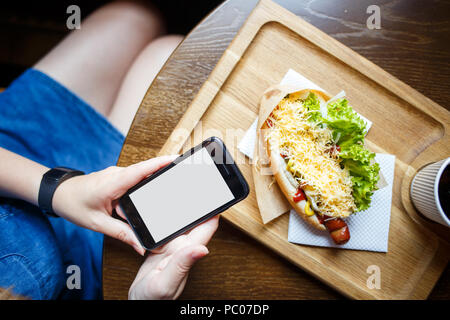 Junge Frau mit "App auf dem Smartphone im Cafe Stockfoto