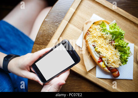 Junge Frau mit "App auf dem Smartphone im Cafe Stockfoto