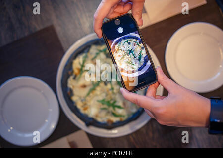 Junge Frau mit Foto von Pizza im Restaurant Stockfoto