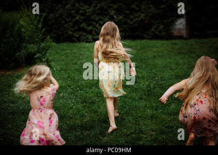 Das Aussehen der drei kleinen Mädchen in einem Kleid im Park läuft gekleidet Stockfoto