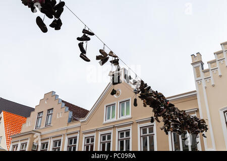 Abgebrochene sportlichen Schuhen hängen an elektrischen Draht über städtische Straße, Straße auf die Altstadt von Flensburg, Deutschland Stockfoto