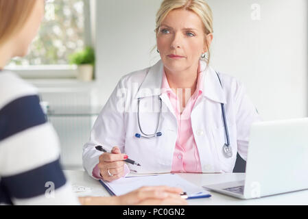 Aufnahme der Ärztin im Gespräch mit Frau und der Diskussion über die medizinischen Bericht in dem Zimmer, in dem der Arzt. Stockfoto