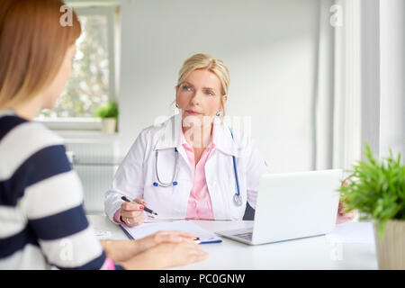 Aufnahme der Ärztin im Gespräch mit Frau und der Diskussion über die medizinischen Bericht in dem Zimmer, in dem der Arzt. Stockfoto